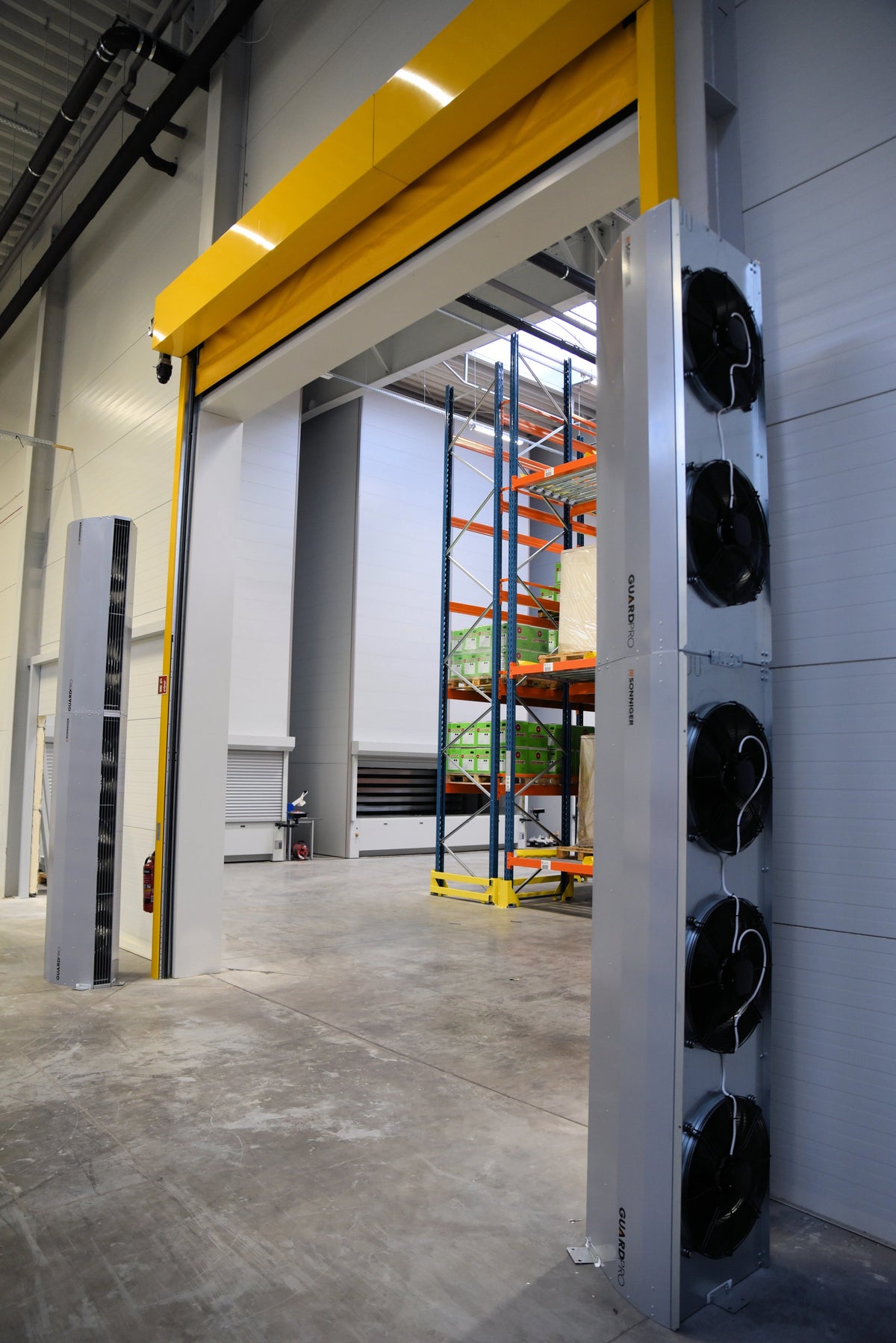 Rideau d'air chaud verticale GUARD PRO à proximité d'une porte en entrepôt